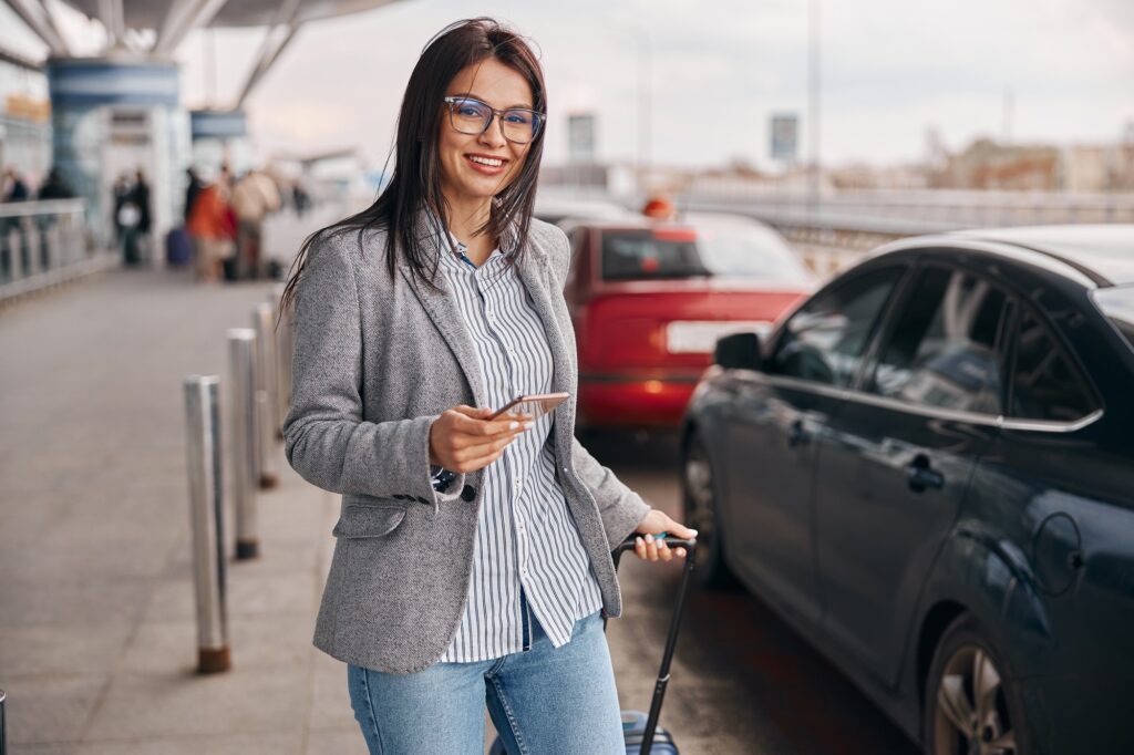 Happy caucasian woman traveller in airport terminal is taking a taxi